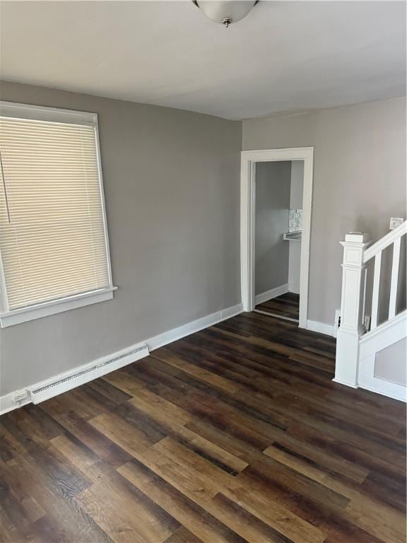 spare room featuring a baseboard heating unit and dark hardwood / wood-style floors