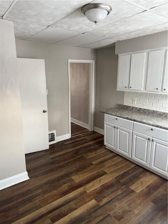 kitchen featuring white cabinetry, decorative backsplash, and dark hardwood / wood-style flooring