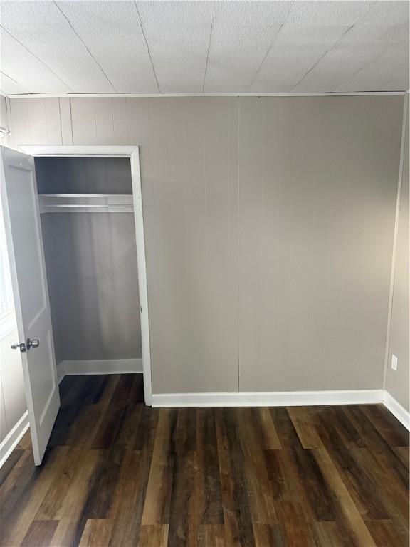 unfurnished bedroom with dark hardwood / wood-style floors and a closet