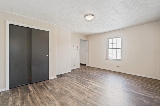 unfurnished bedroom with dark hardwood / wood-style flooring and a closet