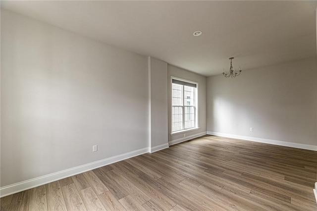 unfurnished room featuring an inviting chandelier and light hardwood / wood-style flooring