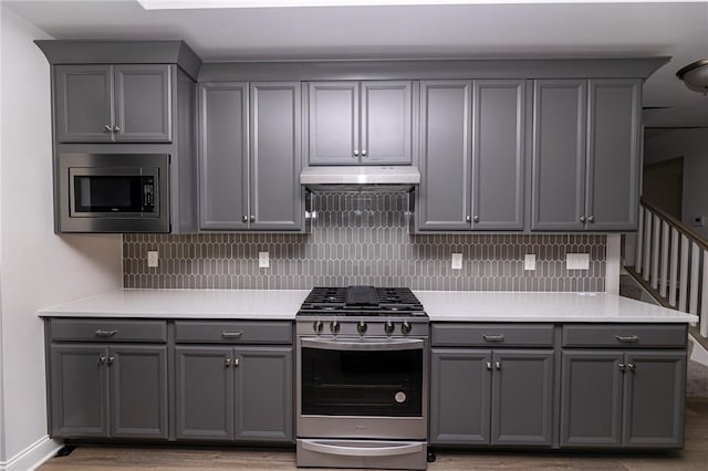 kitchen with stainless steel appliances, gray cabinets, and decorative backsplash