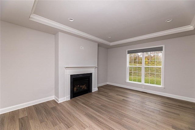 unfurnished living room with crown molding, wood-type flooring, and a raised ceiling