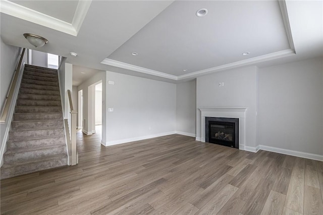 unfurnished living room featuring crown molding, a tray ceiling, and hardwood / wood-style flooring