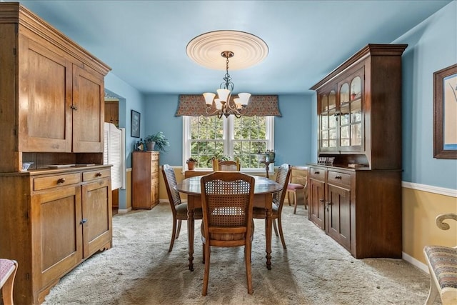 dining space with light colored carpet and a chandelier