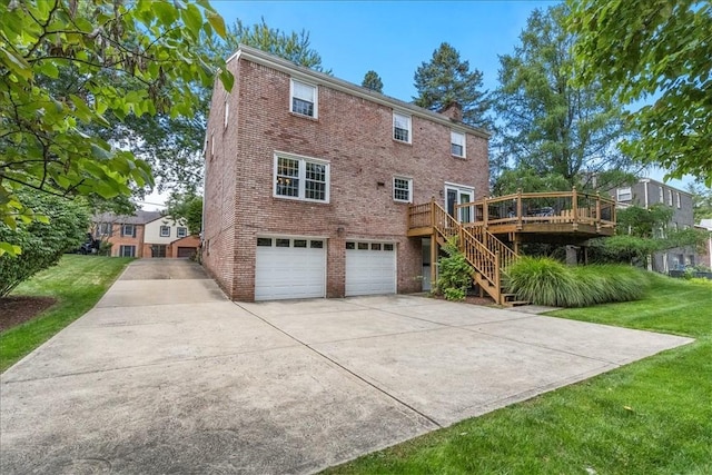 rear view of property with a garage, a yard, and a deck