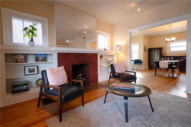 living area with a notable chandelier, hardwood / wood-style flooring, and built in features