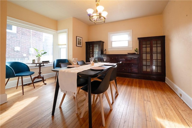 dining space featuring light wood-type flooring and an inviting chandelier