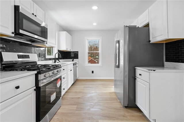 kitchen with sink, appliances with stainless steel finishes, white cabinetry, light stone counters, and decorative backsplash