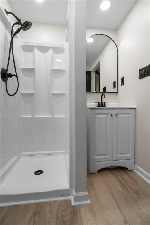 bathroom with a shower, hardwood / wood-style floors, and vanity