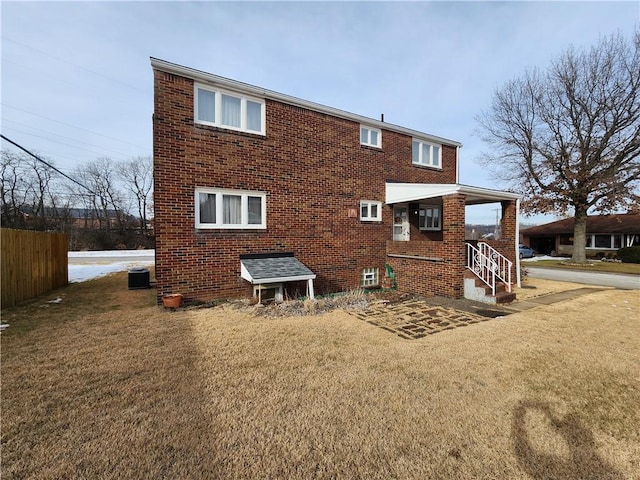 rear view of house with central AC and a lawn