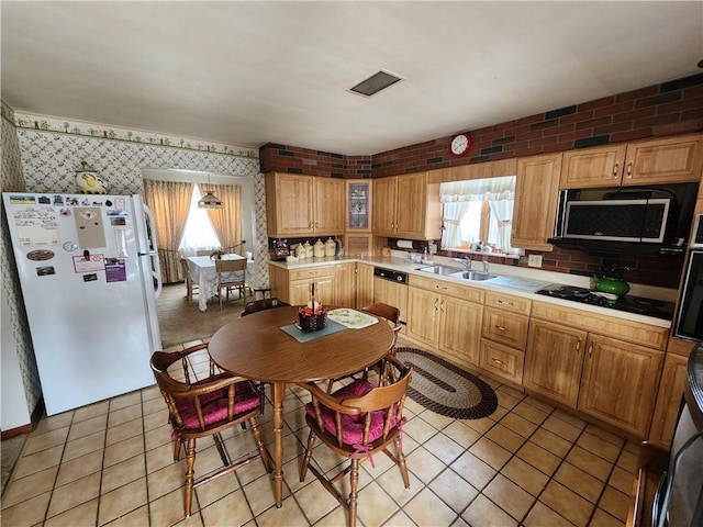 kitchen with sink, light tile patterned floors, paneled dishwasher, black gas stovetop, and white fridge