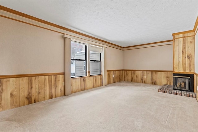 unfurnished living room with ornamental molding, carpet floors, a textured ceiling, and wood walls