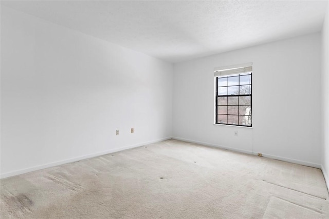 spare room with light colored carpet and a textured ceiling