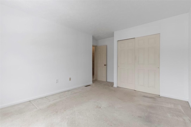 unfurnished bedroom with light carpet and a closet