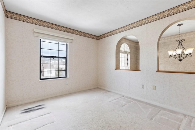 spare room with carpet flooring and a chandelier