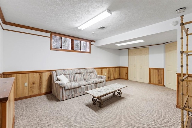 living room featuring crown molding, light carpet, a textured ceiling, and wood walls