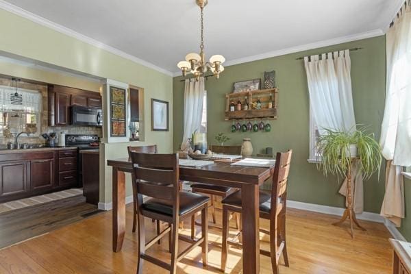 dining room with ornamental molding, sink, and light wood-type flooring