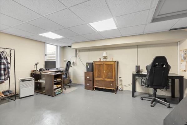 office area featuring a paneled ceiling and concrete floors