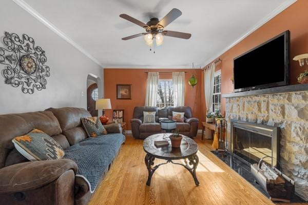 living room with hardwood / wood-style flooring, a fireplace, crown molding, and ceiling fan