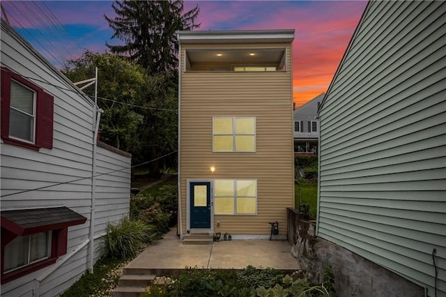 back house at dusk featuring a patio