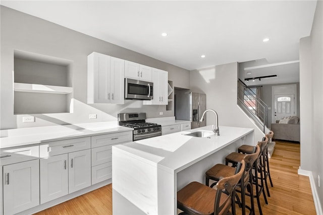 kitchen with stainless steel appliances, a kitchen island with sink, a breakfast bar area, and white cabinets