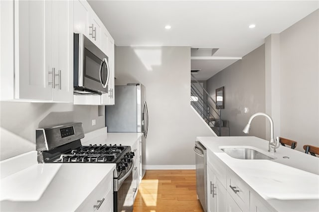 kitchen featuring white cabinetry, appliances with stainless steel finishes, sink, and light wood-type flooring