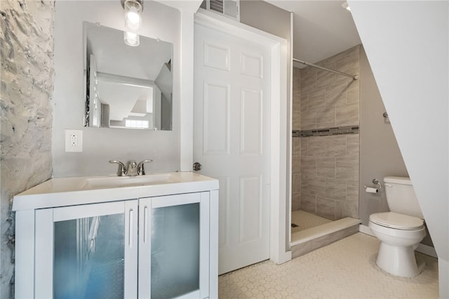 bathroom featuring vanity, a tile shower, and toilet