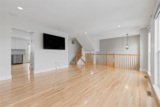 unfurnished living room with a chandelier and light hardwood / wood-style flooring