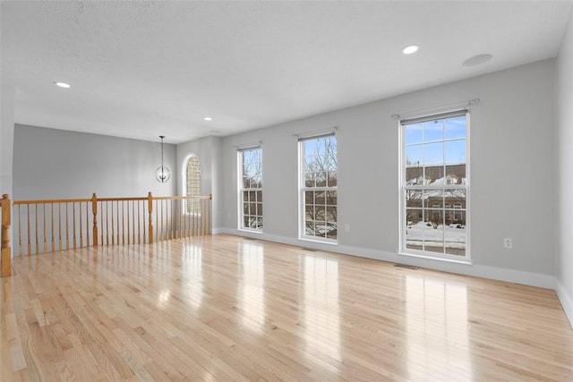 empty room featuring light hardwood / wood-style flooring and a chandelier