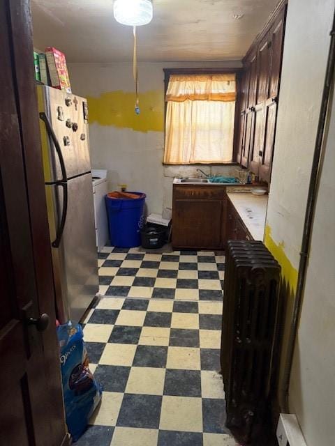 kitchen with a baseboard heating unit, washer / dryer, sink, and stainless steel fridge