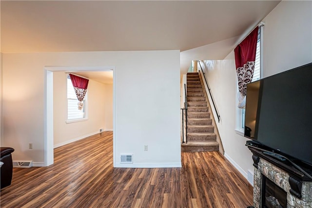 living room with dark hardwood / wood-style floors and a stone fireplace