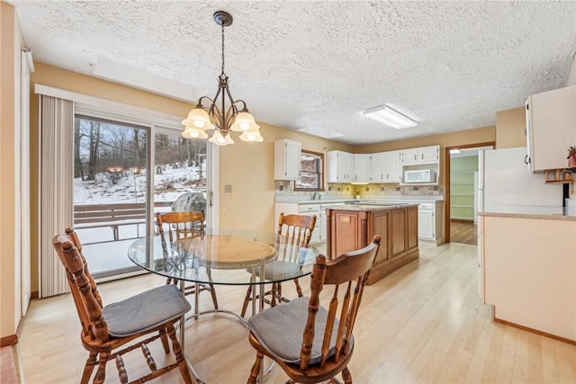 dining space with a notable chandelier, light hardwood / wood-style flooring, and a textured ceiling