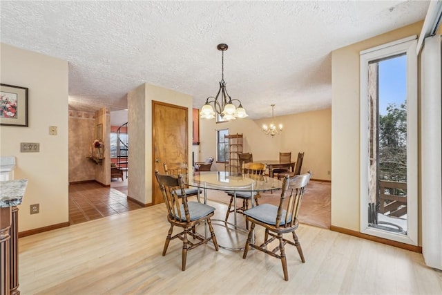 dining room with a textured ceiling, a chandelier, and light wood-type flooring