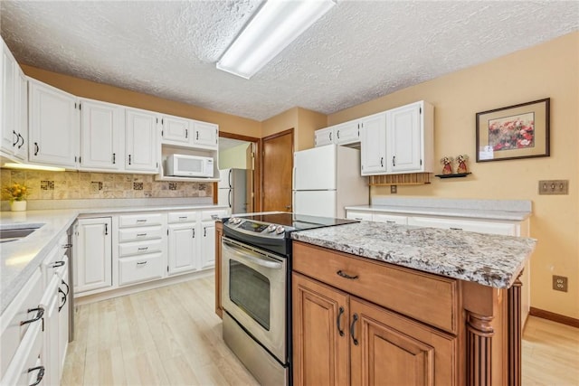 kitchen with white appliances, light hardwood / wood-style floors, white cabinets, and a kitchen island