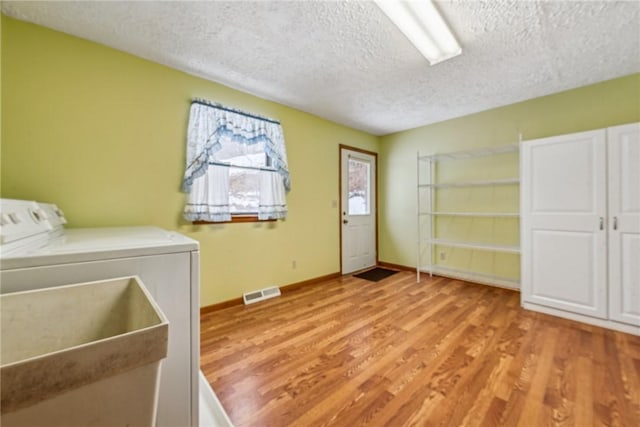 laundry room featuring washer / clothes dryer, sink, light hardwood / wood-style flooring, and a textured ceiling