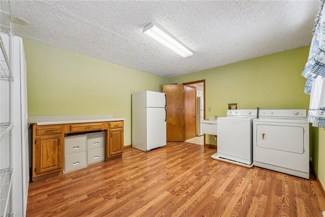 clothes washing area featuring a textured ceiling, washing machine and clothes dryer, and light wood-type flooring