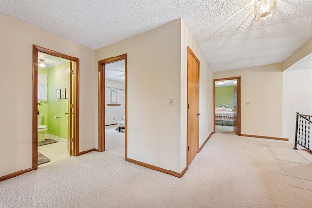 hall with light carpet and a textured ceiling