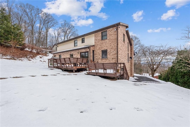 snow covered rear of property with a wooden deck