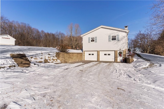 115 Mill Creek Rd, Mill Creek, PA 16145 - view of snowy exterior featuring an attached garage and a chimney