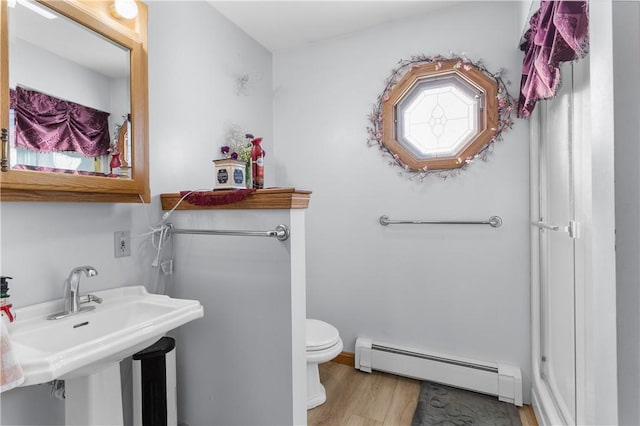 bathroom with a baseboard heating unit, wood-type flooring, and toilet