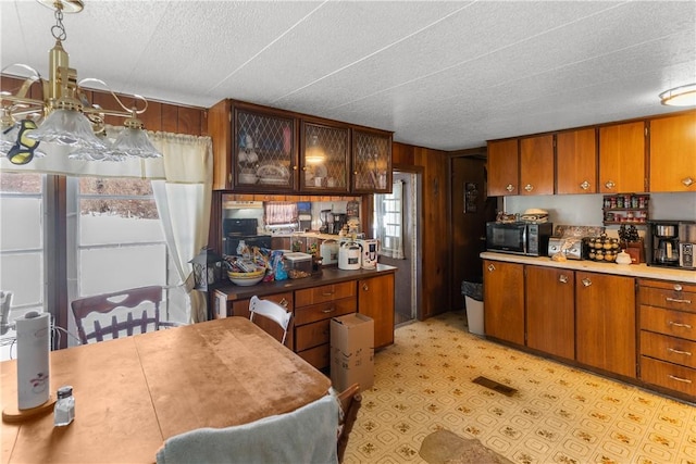 115 Mill Creek Rd, Mill Creek, PA 16145 - kitchen with black microwave, a textured ceiling, a chandelier, brown cabinetry, and light floors