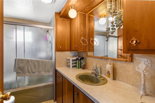 bathroom featuring vanity, decorative backsplash, shower / bath combination with glass door, and a textured ceiling