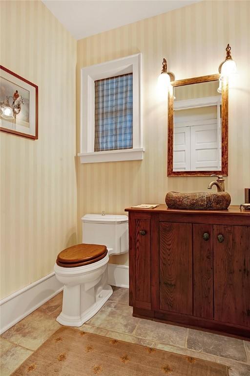 bathroom with vanity, baseboards, toilet, and wallpapered walls