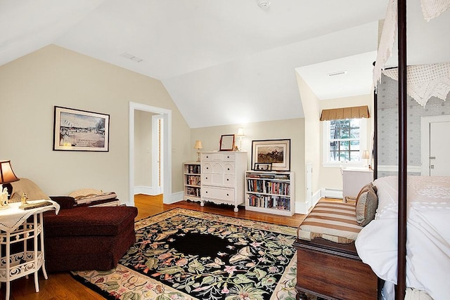living area with visible vents, baseboard heating, vaulted ceiling, wood finished floors, and baseboards
