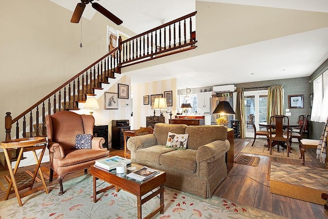 living room featuring ceiling fan, wood-type flooring, a wall mounted AC, and a high ceiling