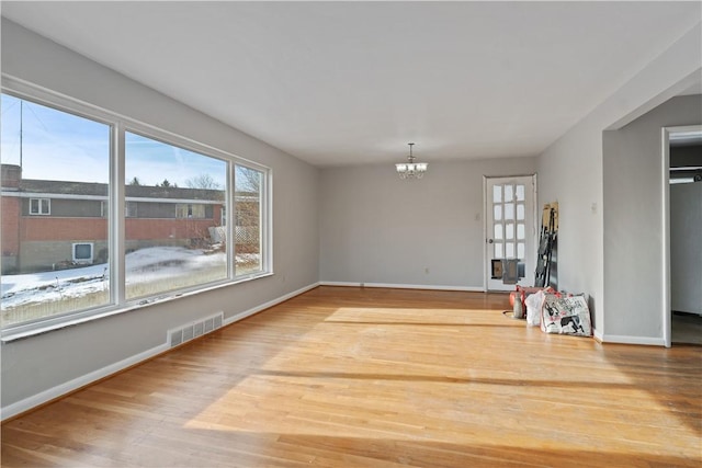 empty room featuring wood-type flooring and a chandelier