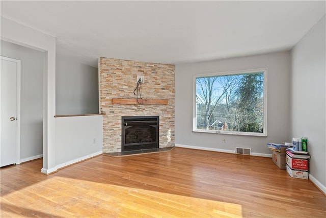 unfurnished living room featuring wood-type flooring and a stone fireplace