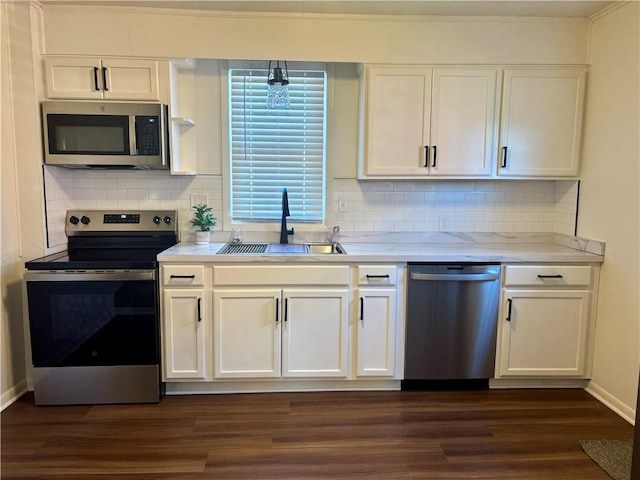 kitchen with sink, appliances with stainless steel finishes, white cabinetry, dark hardwood / wood-style floors, and decorative backsplash