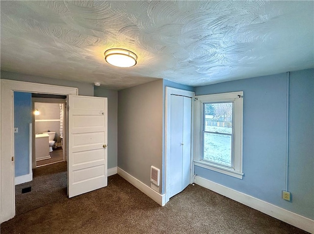 unfurnished bedroom featuring dark carpet, a closet, and a textured ceiling